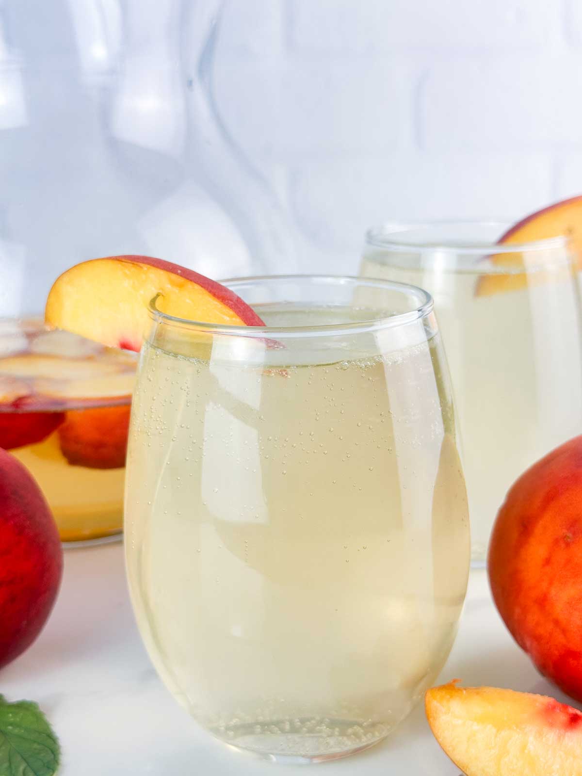 Peach sangria in wine glasses with peaches.