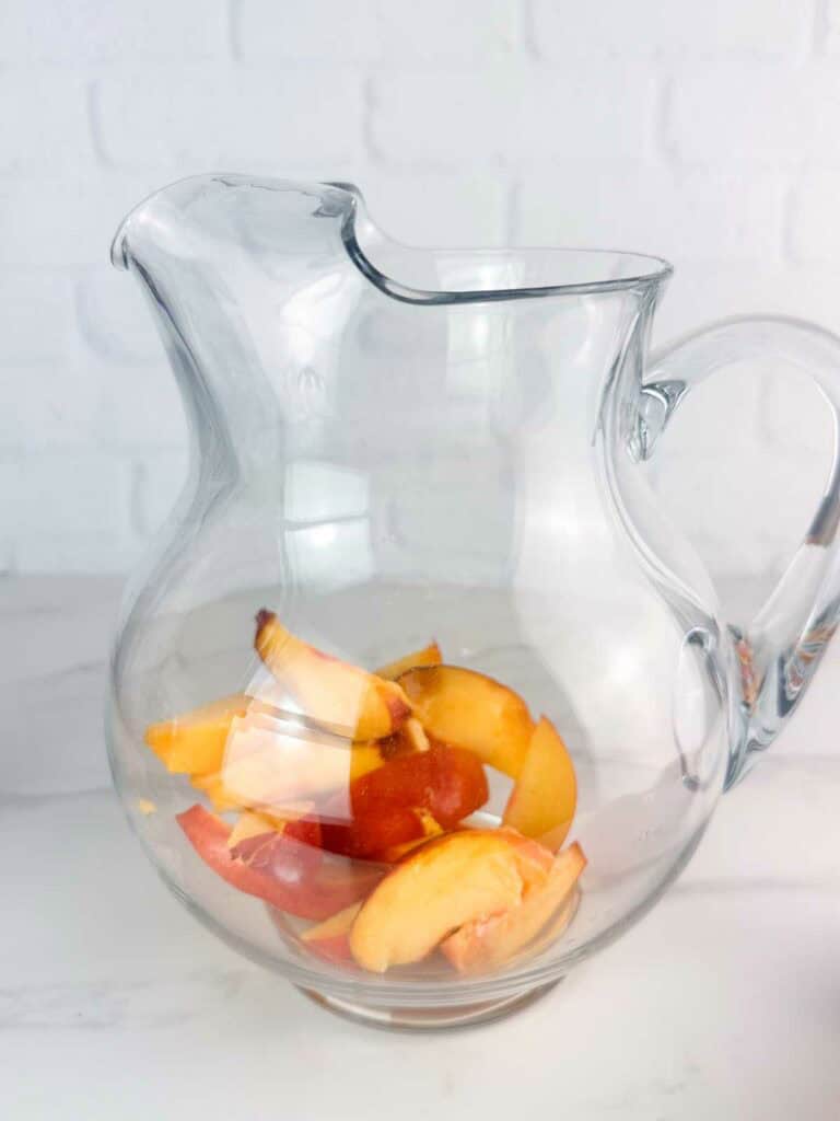 Peaches in a pitcher getting ready to make peach sangria.