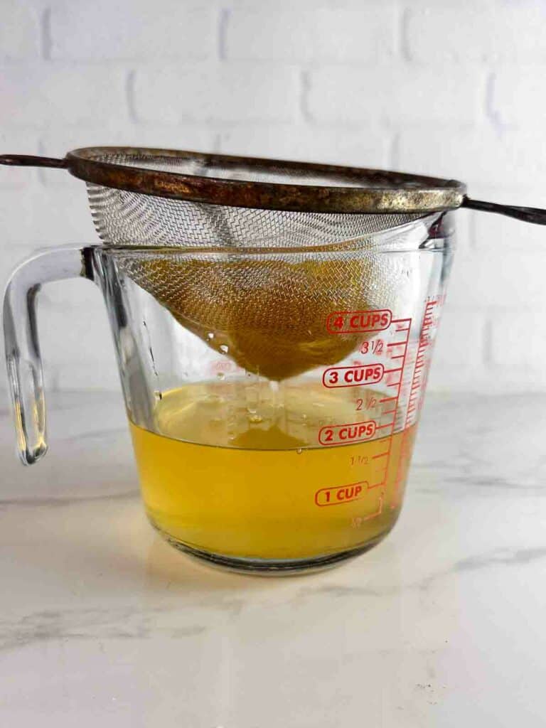 Straining peaches out of peach simple syrup.