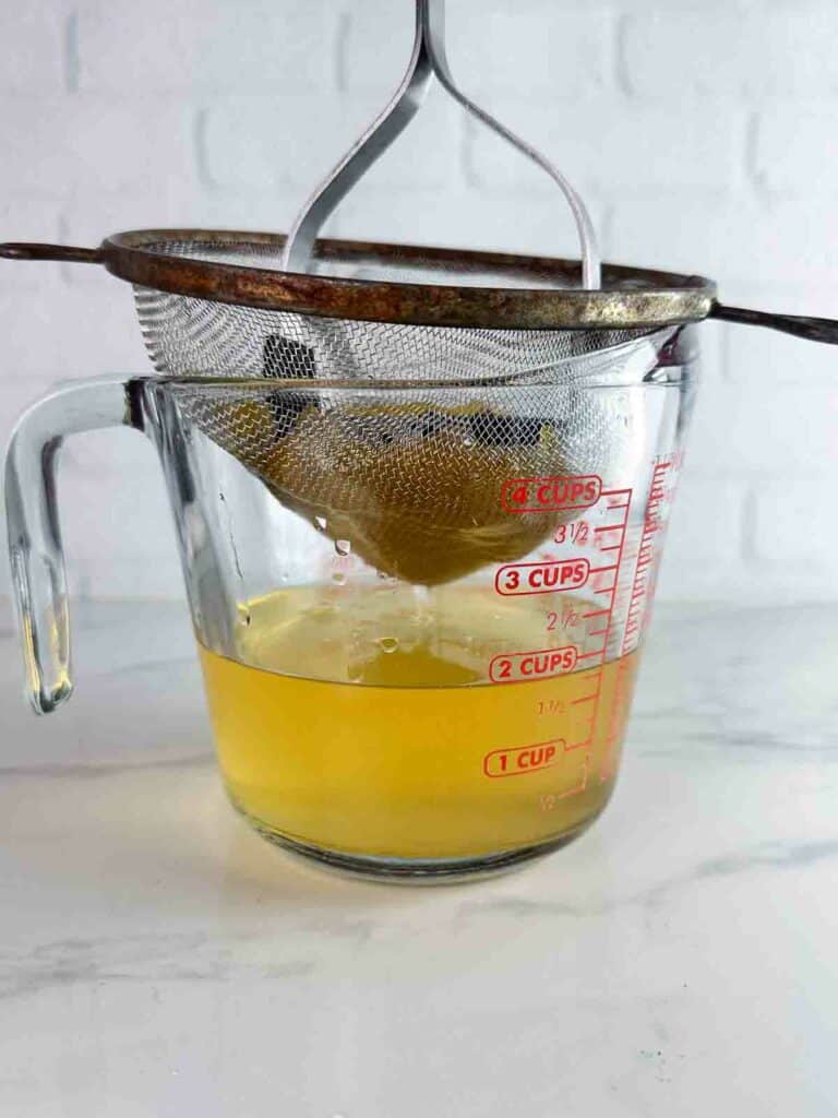 Straining peaches out of peach simple syrup.