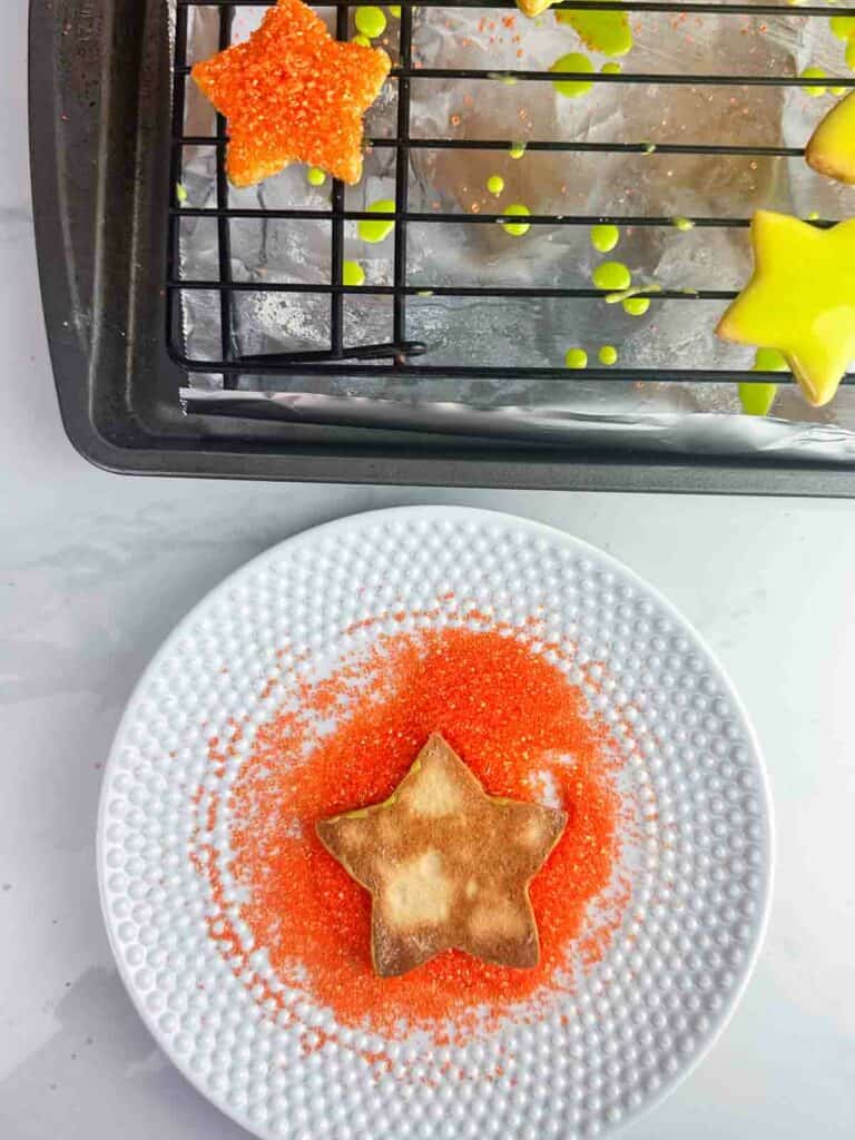 Star sugar cookie dipped in orange glitter sprinkles.