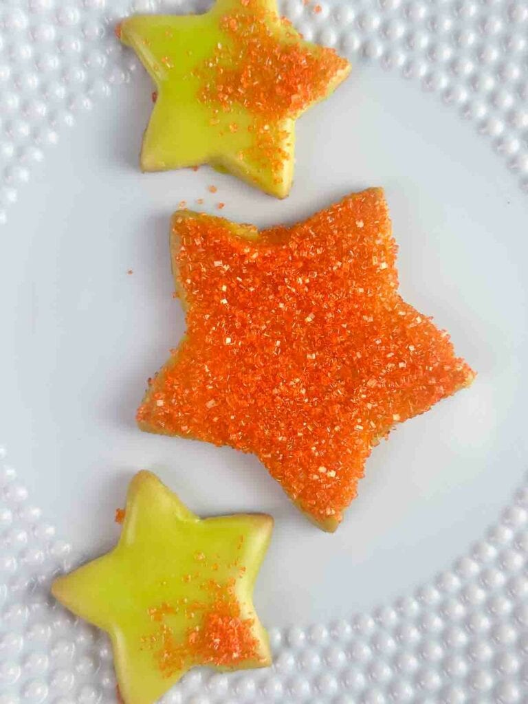 Star sugar cookies with green icing and orange glitter sprinkles.
