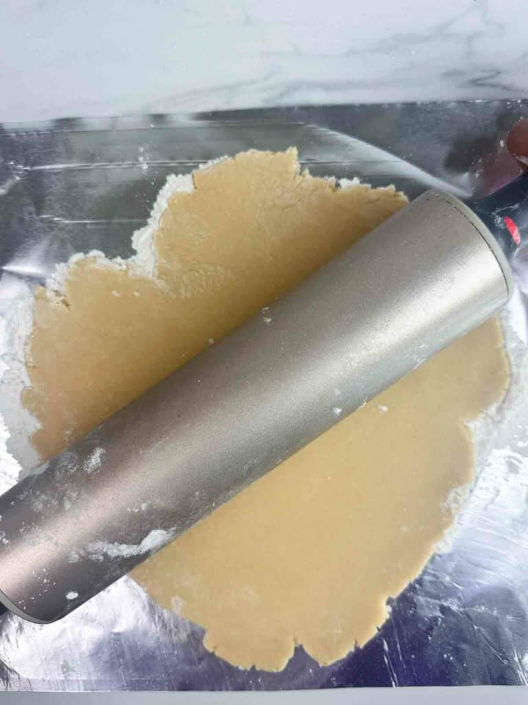 Flattening out sugar cookie dough with a rolling pin.