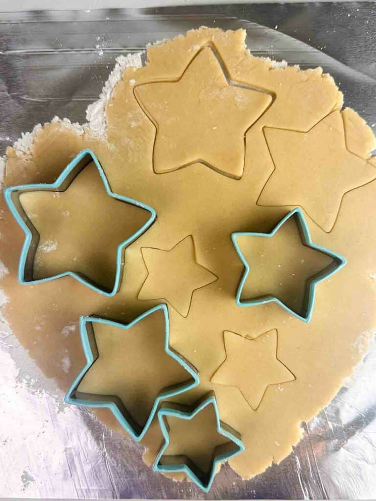 Using a star shaped cookie cutter to cut out cookie shapes.