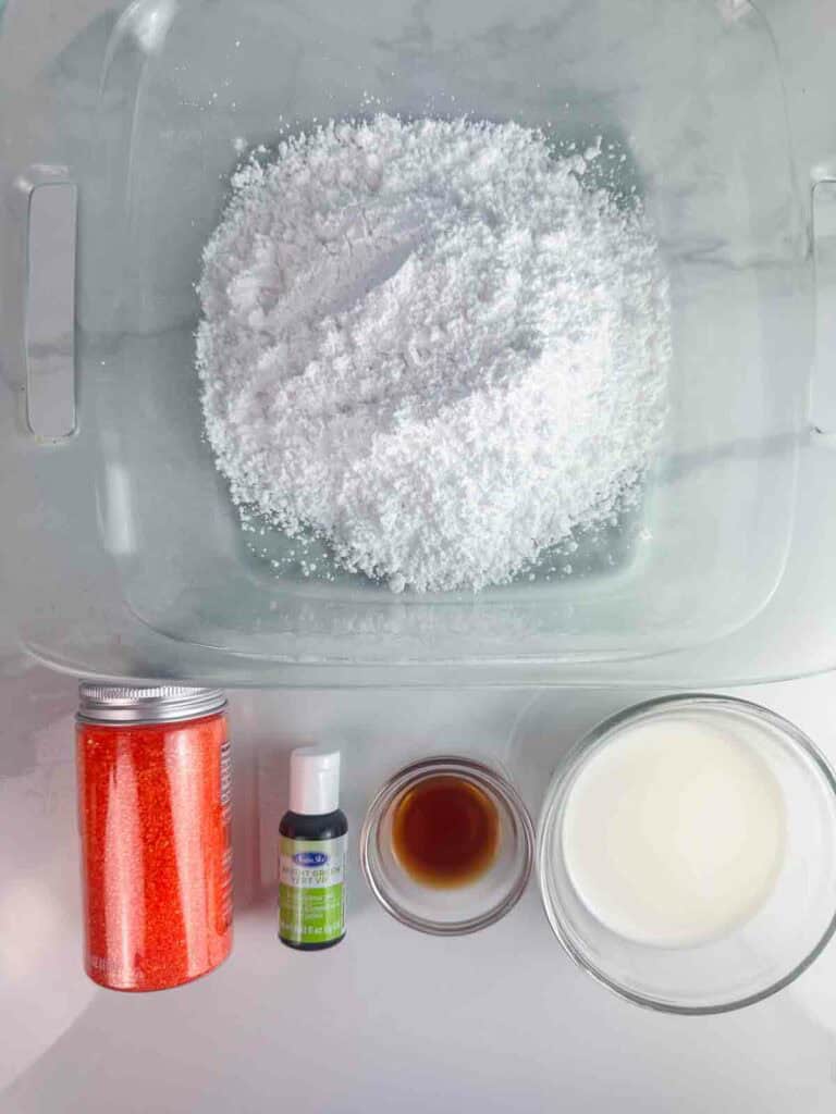 Ingredients for sugar cookie icing: powdered sugar, milk, vanilla extract, bright green food color, and orange glitter sprinkles.