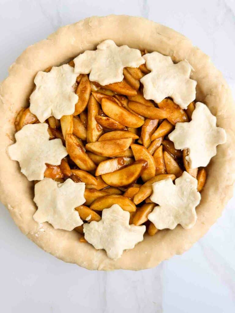 Covering the top of apple pie with leaf shapped pie crust.