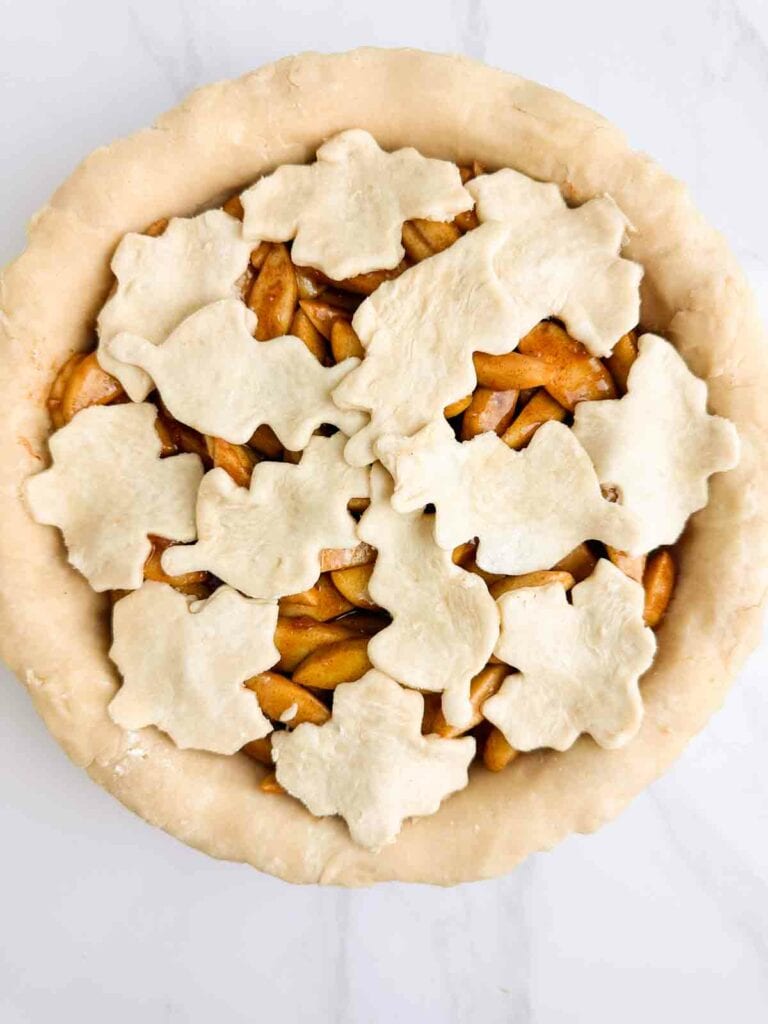 Covering the top of apple pie with leaf shapped pie crust.