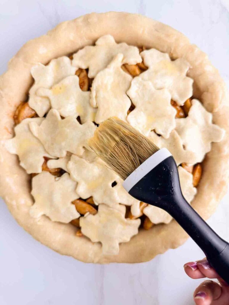 Brush held over apple pie to brush on egg wash.