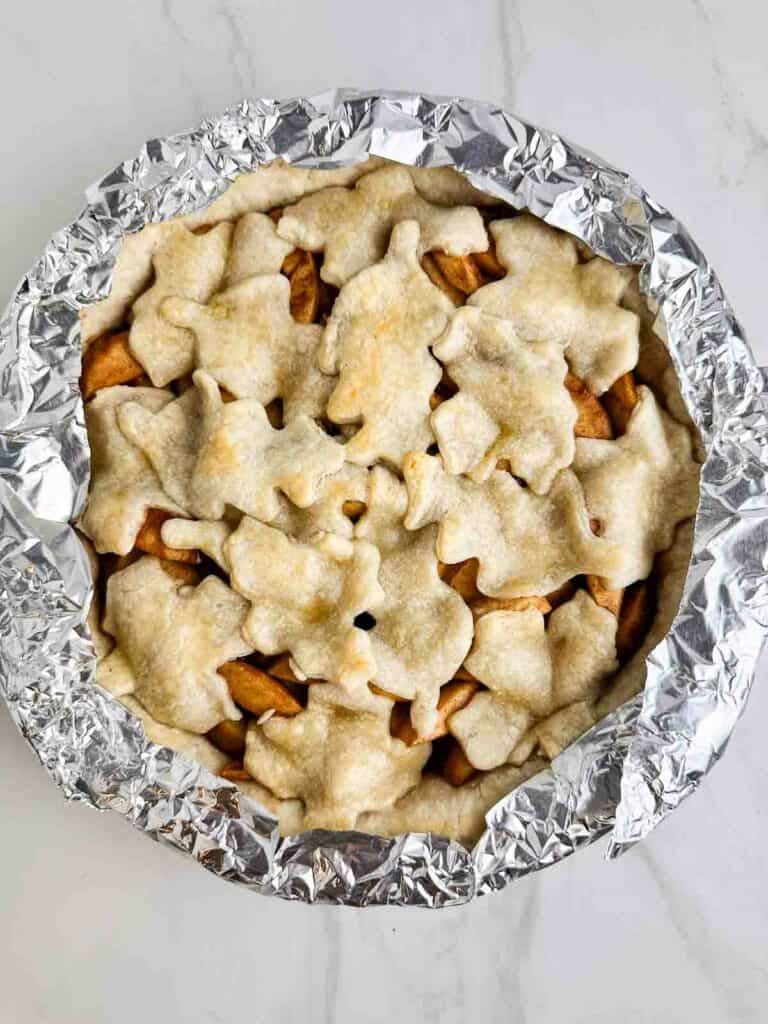 Apple pie with edges covered to keep them from burning right before removing them.