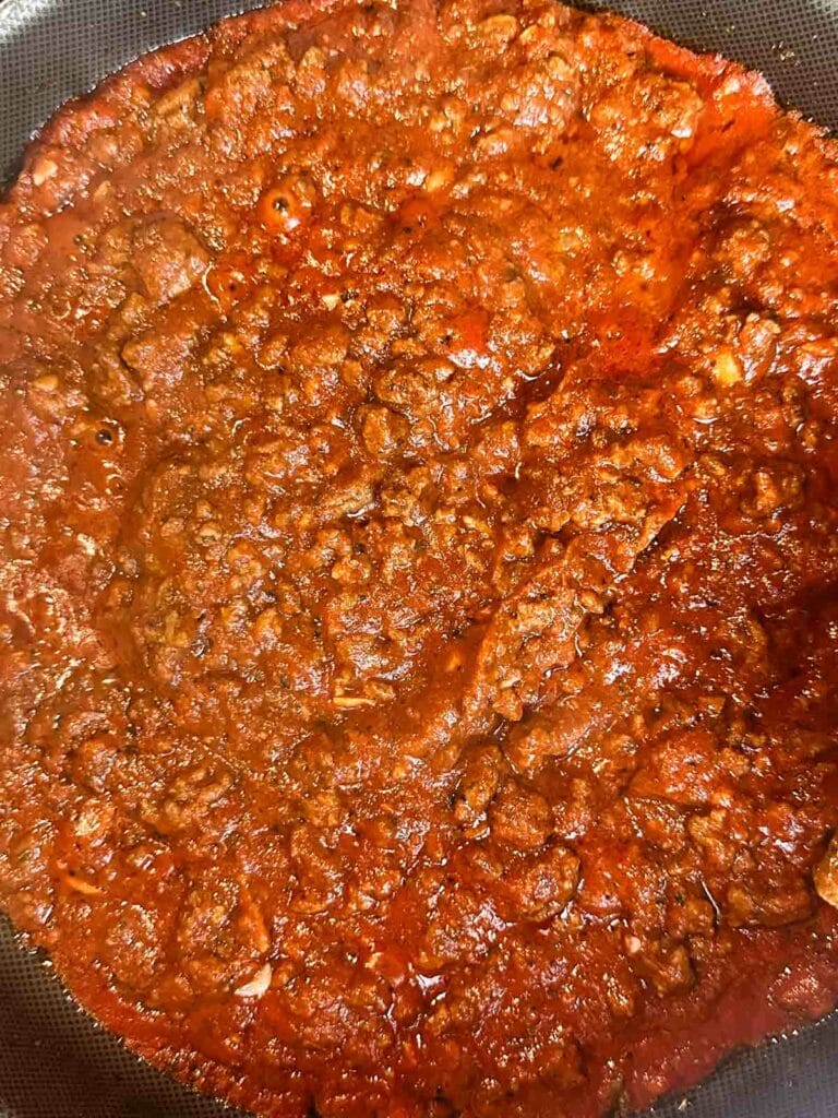 Allowing meat sauce to simmer before adding to favorite pasta.