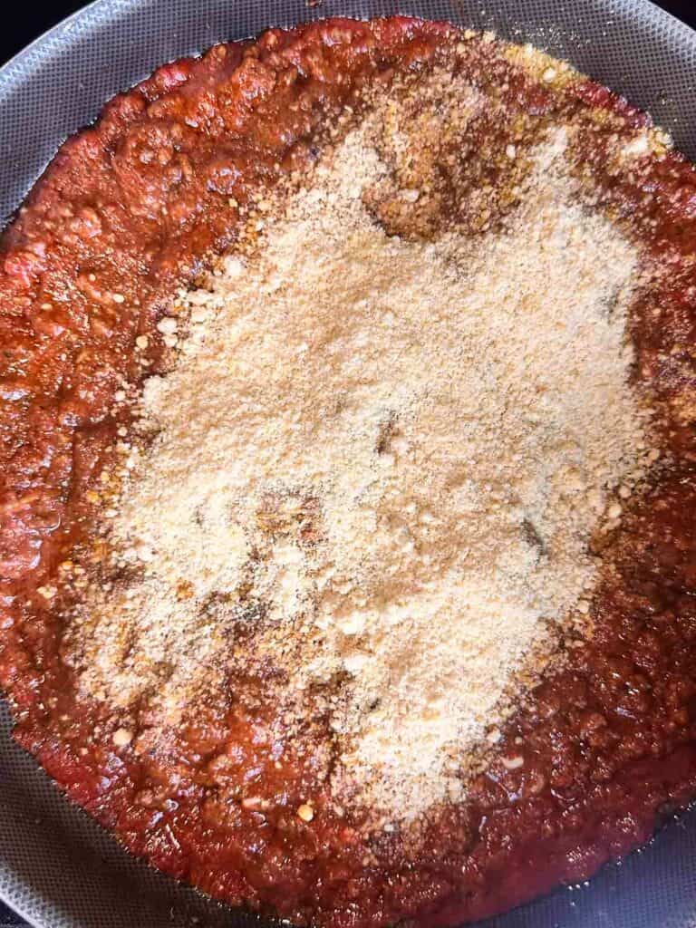 Parm cheese on top of meat sauce in skillet.