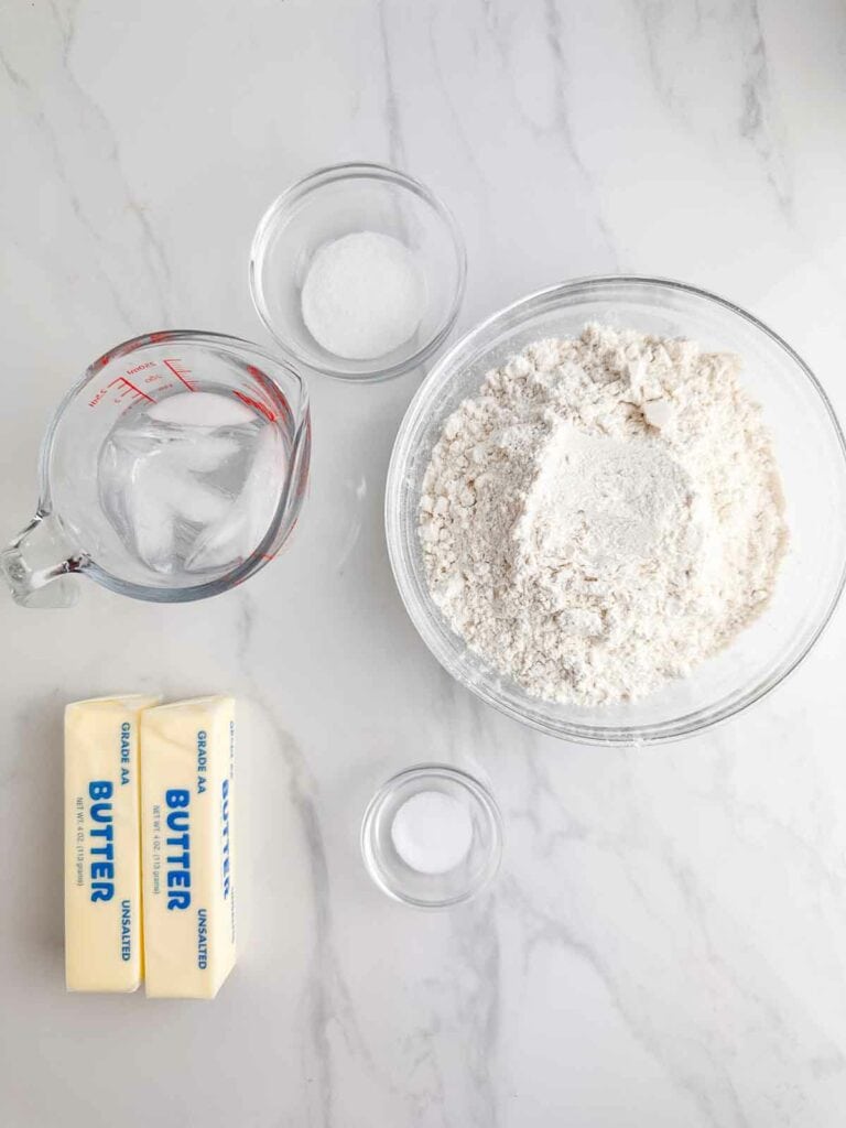 Ingredients for homemade pie crust recipe: sugar, ice water, flour, butter, and salt.