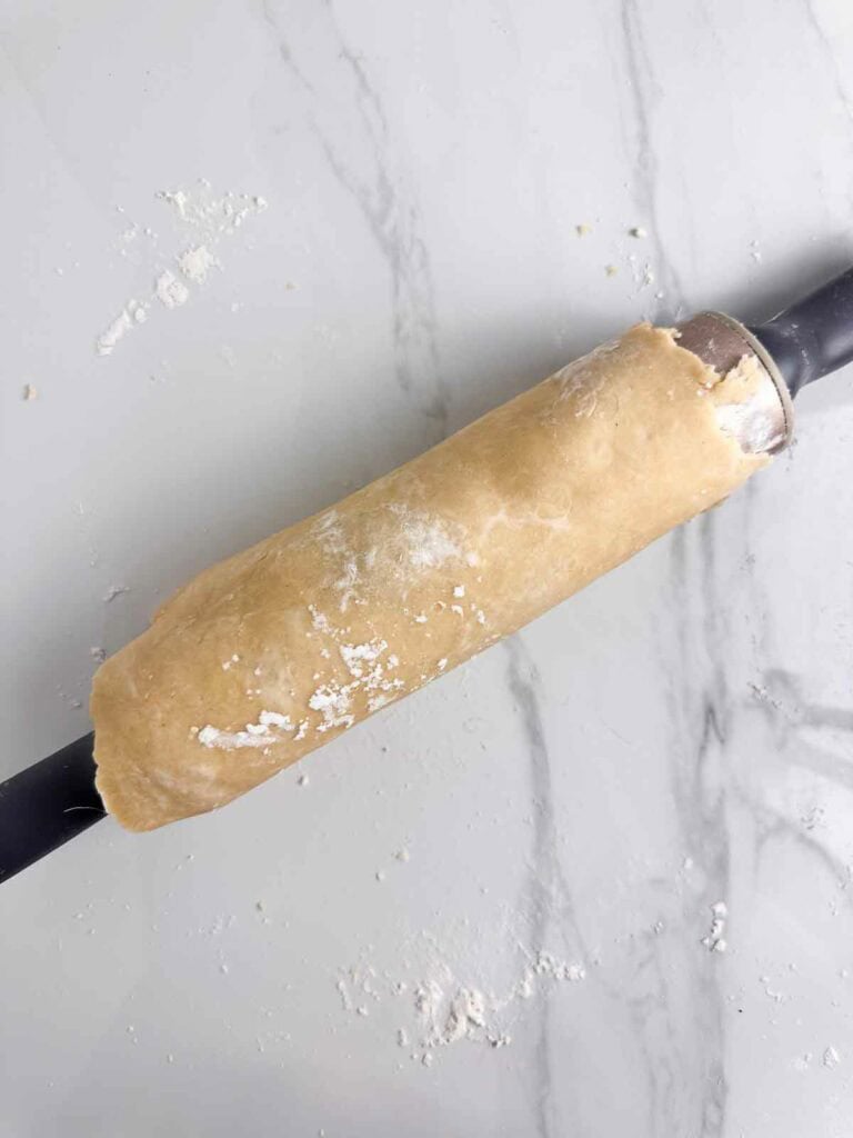 Pie crust rolled loosely on a rolling pine to place over top of a pie dish.