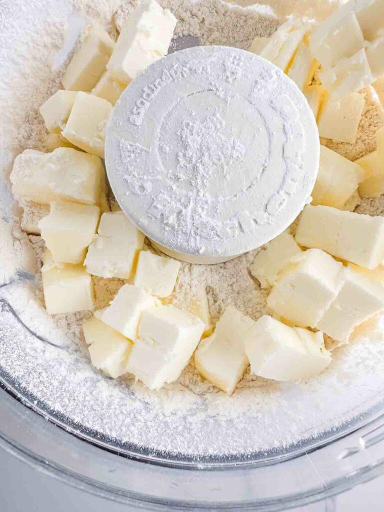 Cubed butter and flour in a food processor bowl.