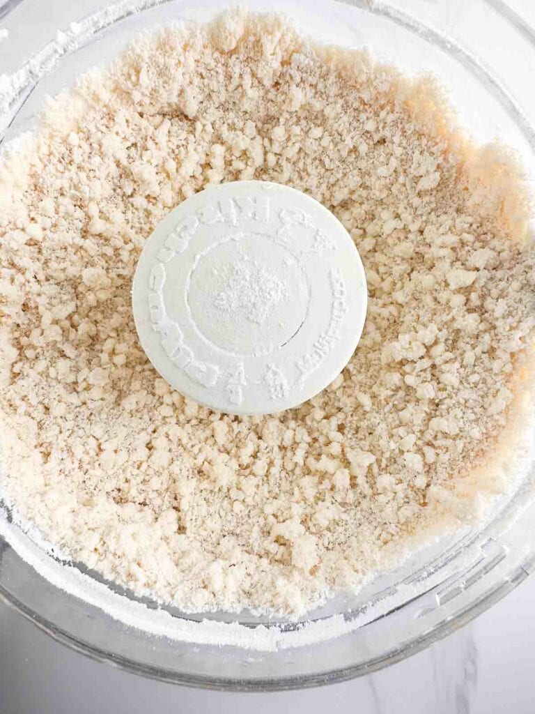 Flour and butter mixed together in the bowl of a food processor.