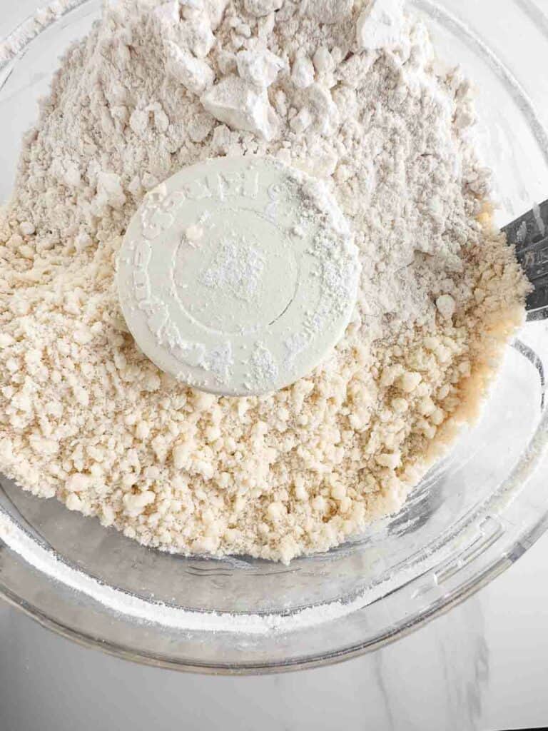 Flour and pie crust dough in a food processor bowl.
