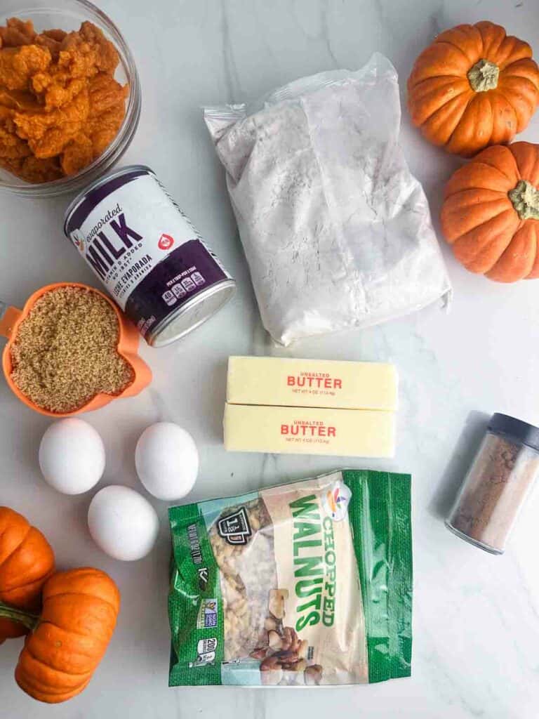 Ingredients for pumpkin praline cake: pumpkin, evaporated milk, spice cake mix, butter, brown sugar, eggs, pumpkin pie spice, and walnuts