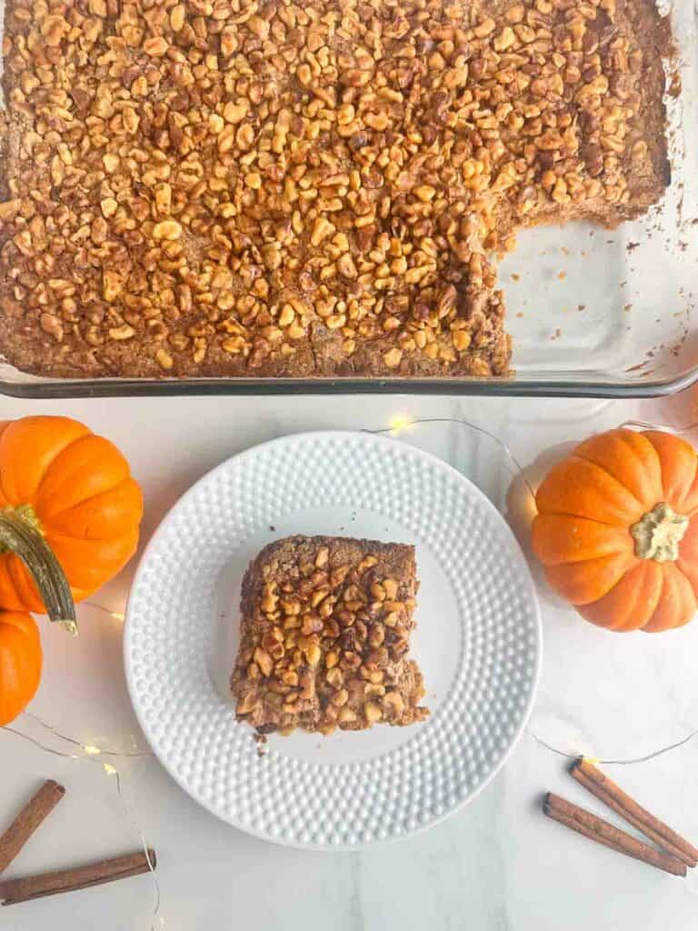 A casserole dish full of pumpkin praline cake with a slice cut out on a plate