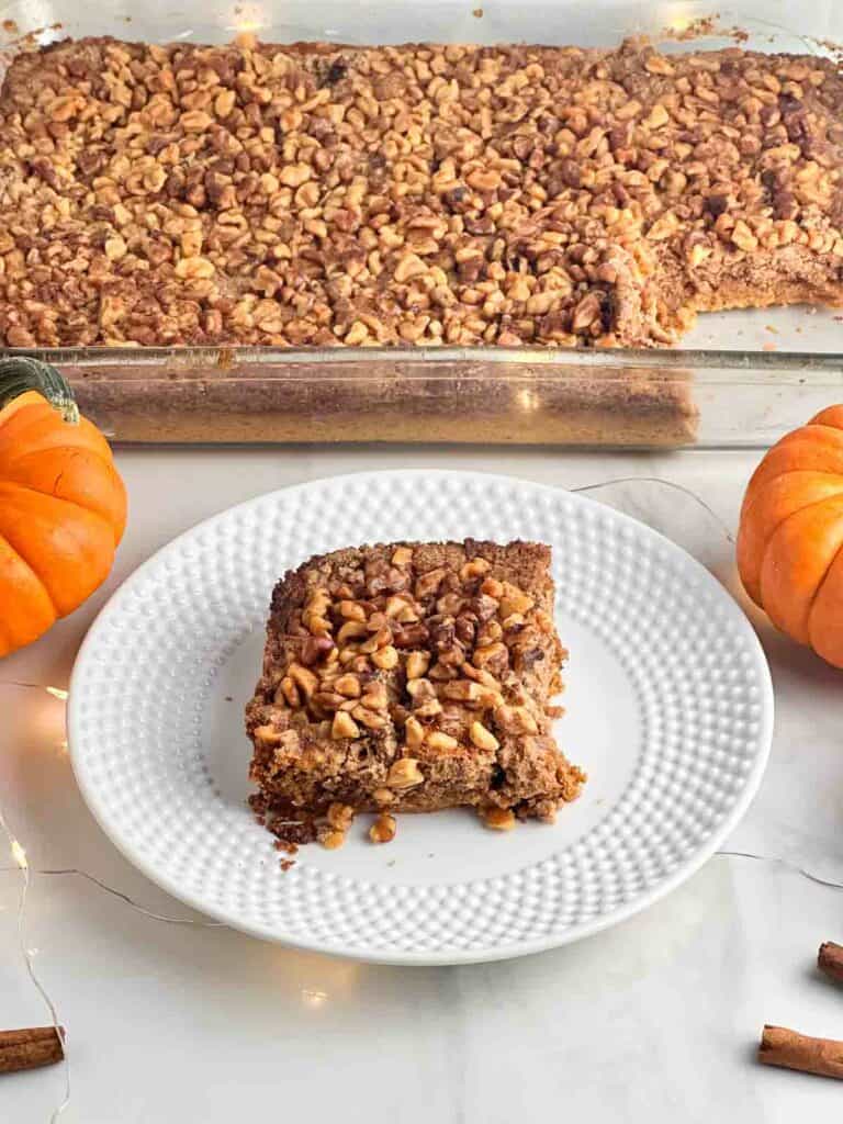 A casserole dish full of pumpkin praline cake with a slice cut out on a plate