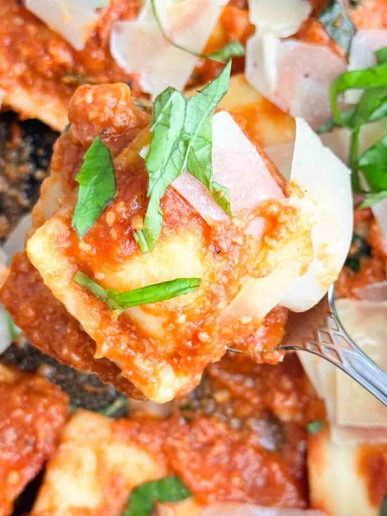 a serving spoon full of ravioli with sauce