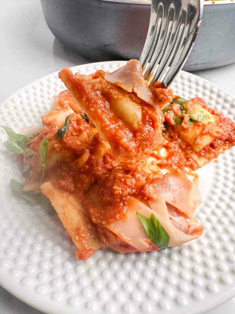 a fork in a ravioli over a plate of ravioli with sauce