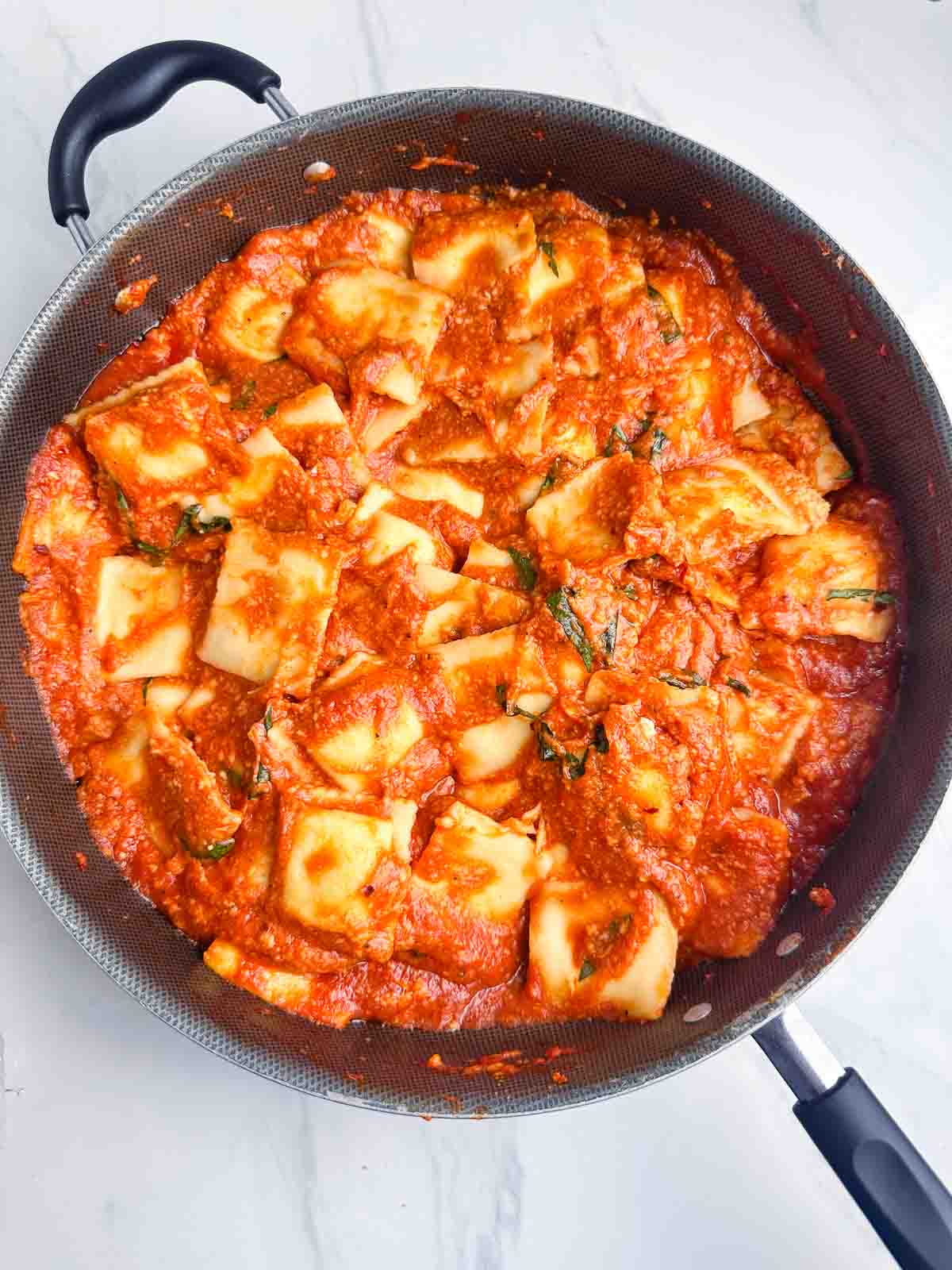 a skillet full of ravioli with sauce