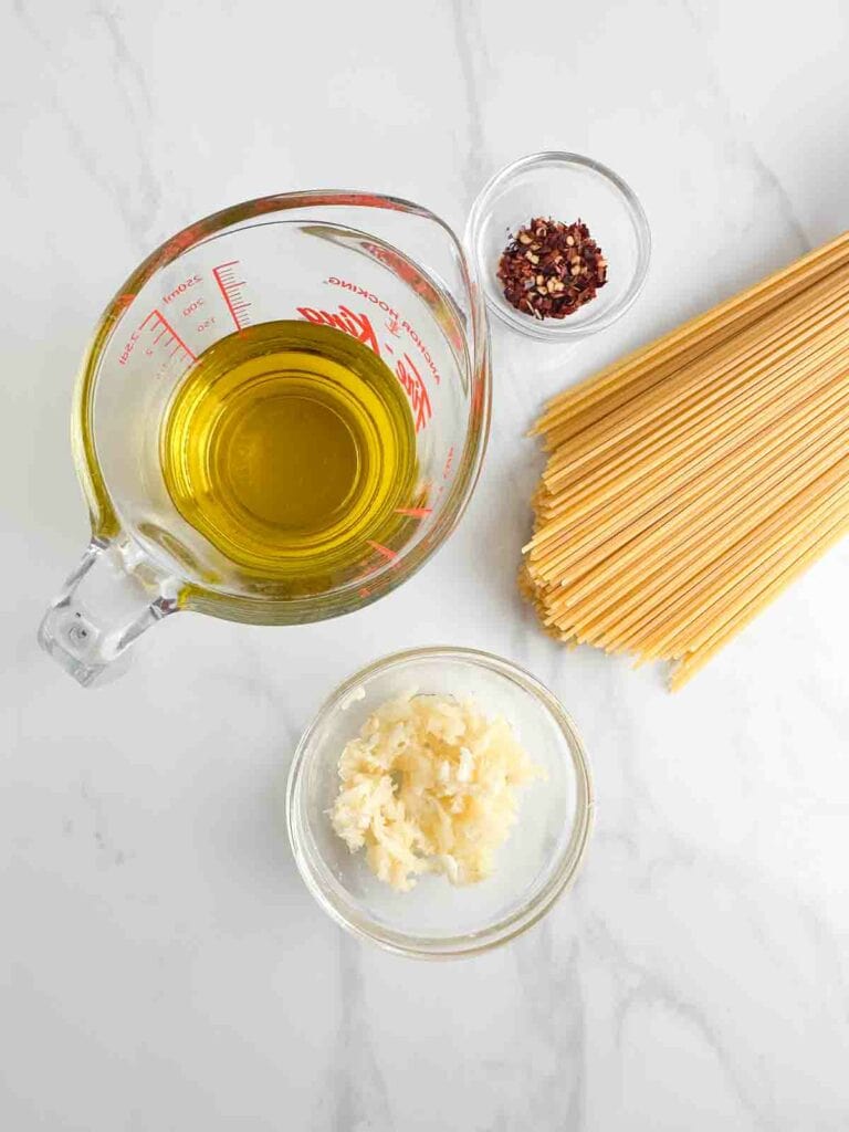 Spaghetti Aglio e Olio ingredients: olive oil, red pepper flakes, spaghetti, and garlic.