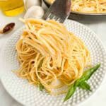 Forkful of Spaghetti Aglio e Olio over a single serving of it.