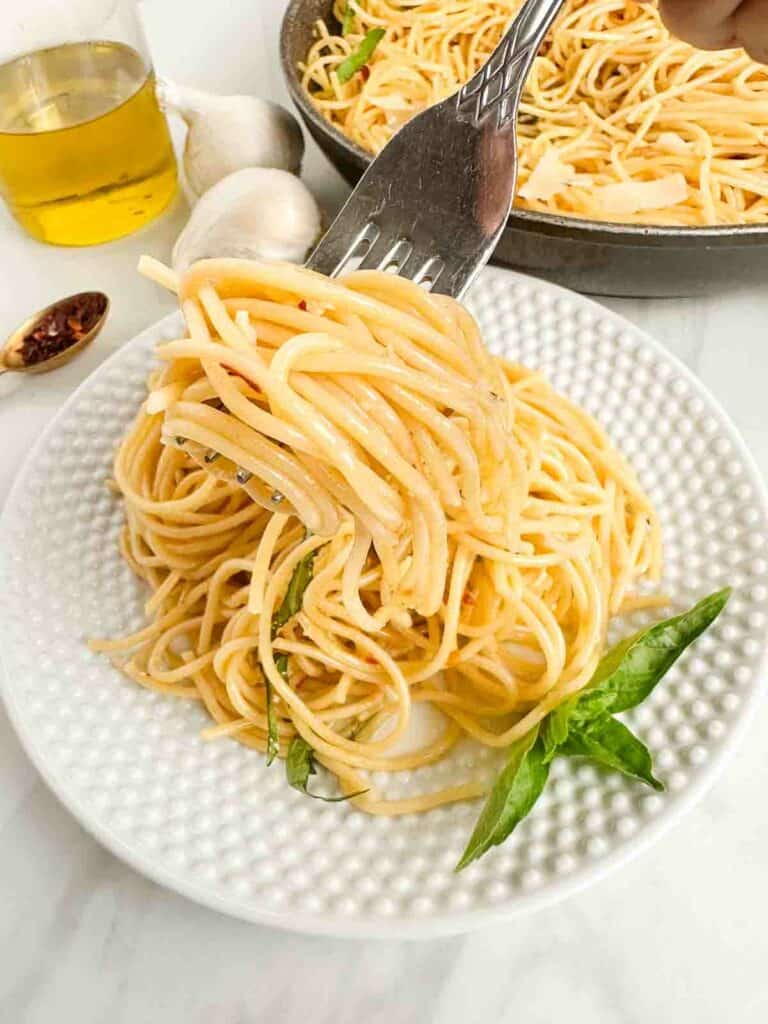Forkful of Spaghetti Aglio e Olio over a single serving of it.
