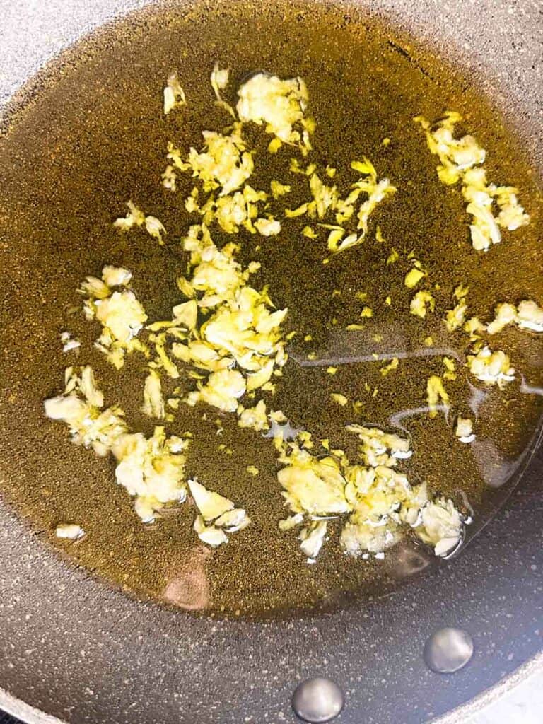 Olive oil and garlic heating in a skillet.