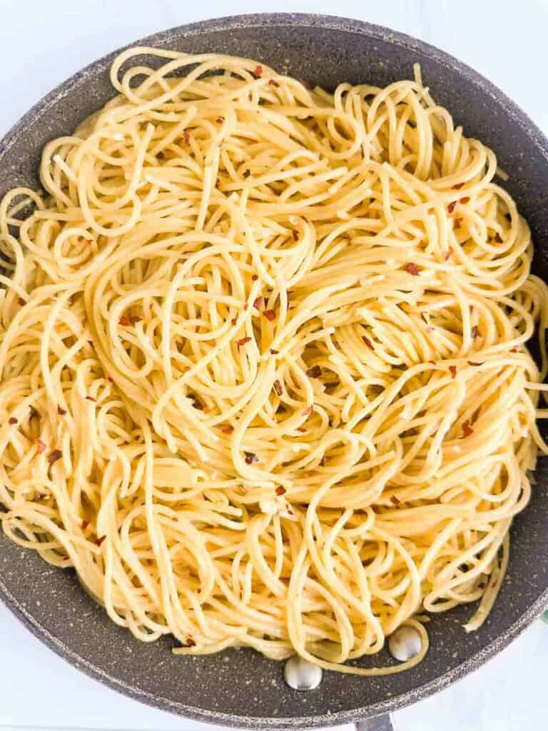 Toss cooked spaghetti with olive oil, red pepper flakes, and garlic.