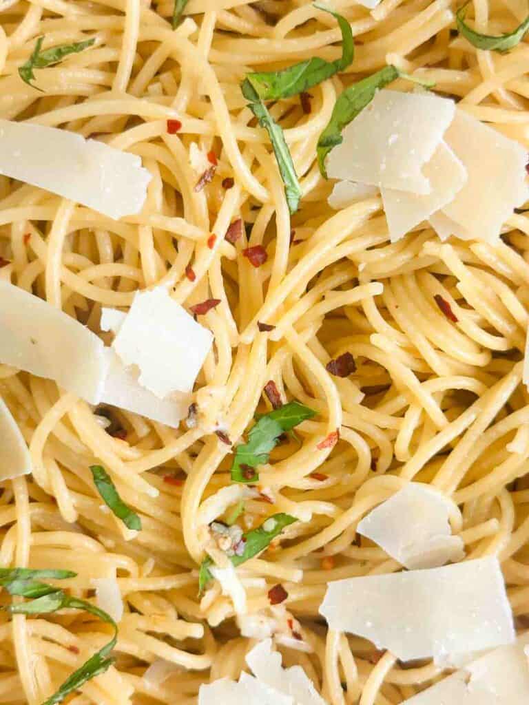 Spaghetti Aglio e Olio topped with parmesan cheese and basil.