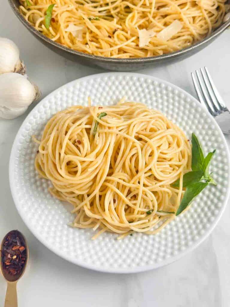 Plate of Spaghetti Aglio e Olio with a skillet next to it.
