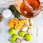 Ingredients for apple cider turkey brine: apple cider, herbs, salt, brown sugar, oranges, onions, green apples, and garlic.