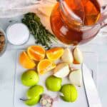 Ingredients for apple cider turkey brine: apple cider, herbs, salt, brown sugar, oranges, onions, green apples, and garlic.