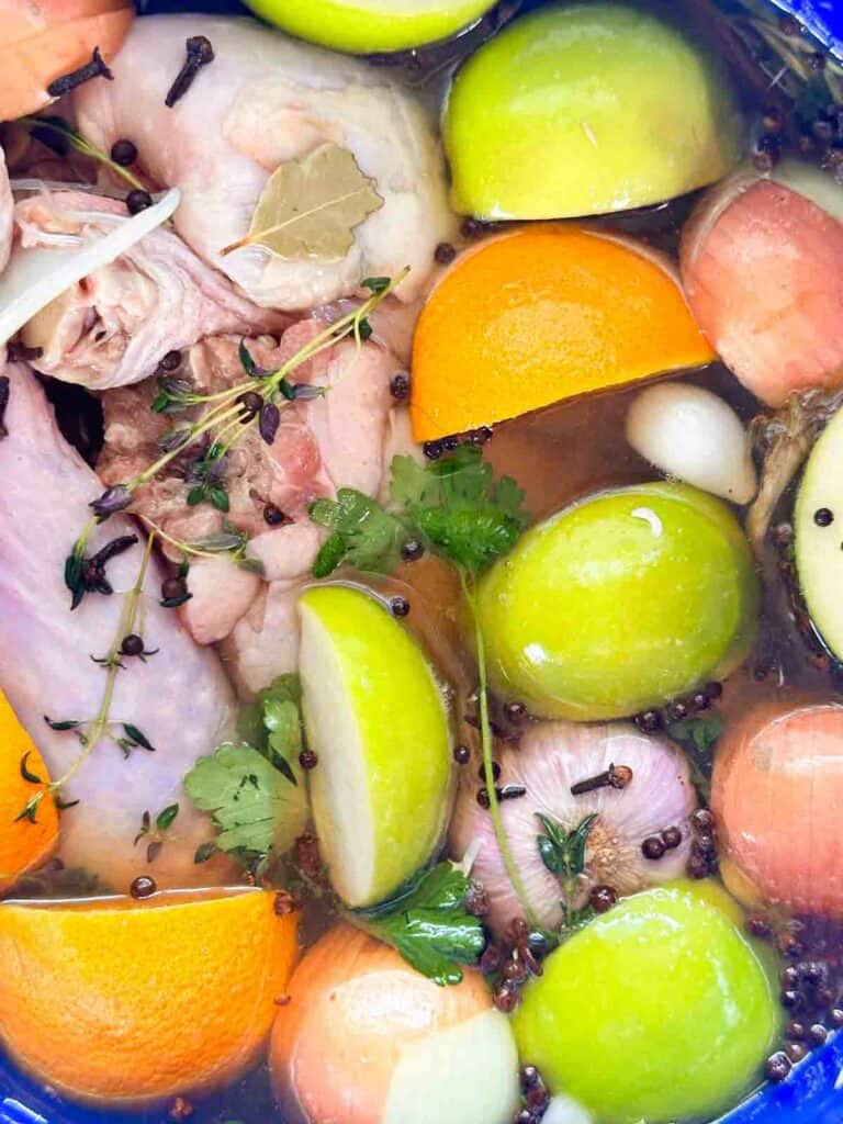 Apple cider turkey brine with onions, apples, oranges, and the turkey itself along with spices and herbs.