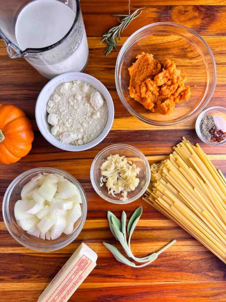 Ingredients for pumpkin pasta: cream, pumpkin puree, parmesan cheese, garlic, onions, sage, pasta, butter, salt, pepper, and red pepper.