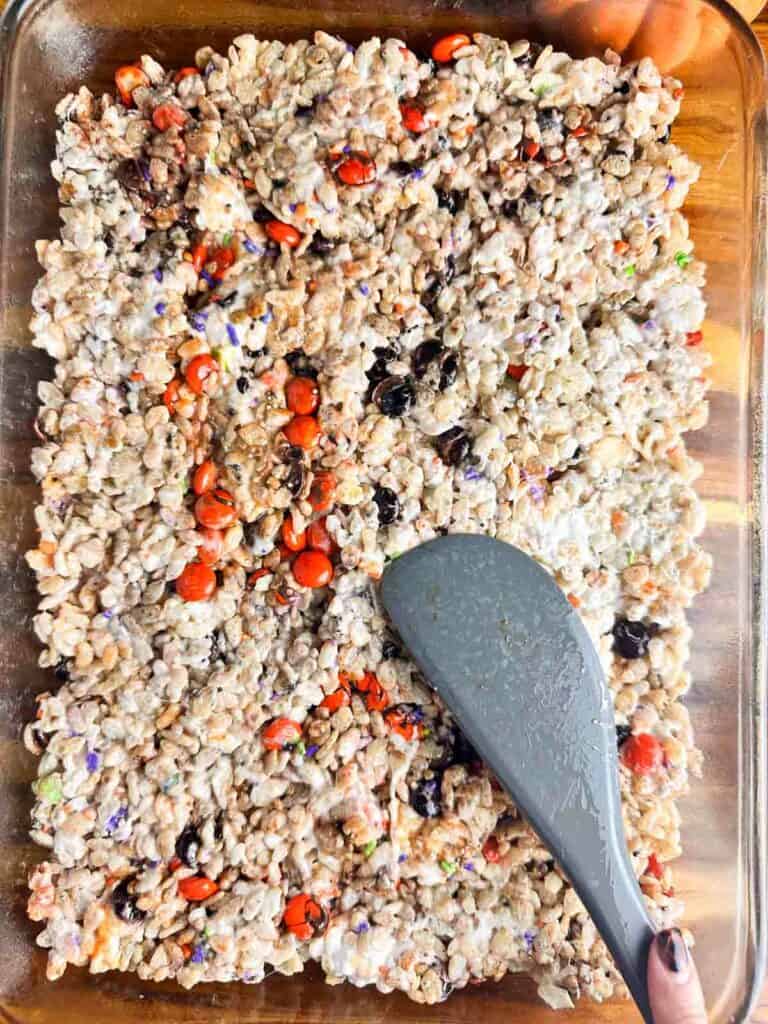 Spreading out Rice Krispie treats using a spatula.