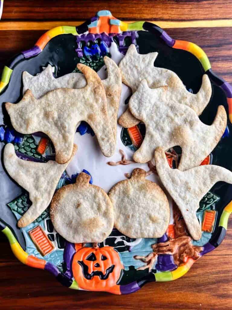 A plate of Halloween tortilla chips shaped like black cats, witch hats, and pumpkins