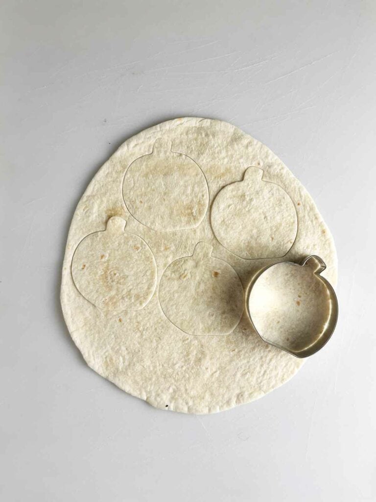 Cut the Halloween tortilla chips using a Halloween cookie cutter like a pumpkin