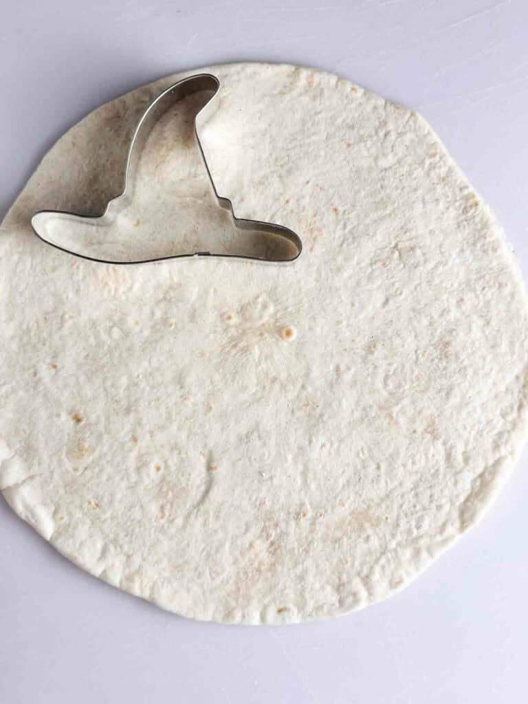 Cut the Halloween tortilla chips using a Halloween cookie cutter like a witch hat