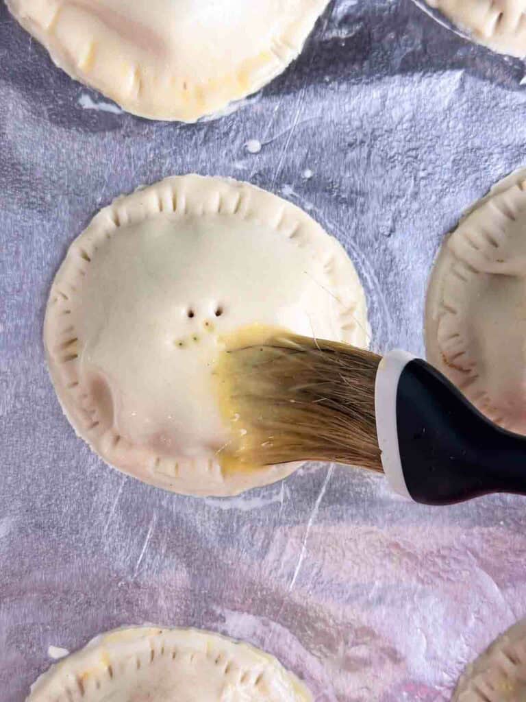 Brushing an egg wash on to mini apple pies.