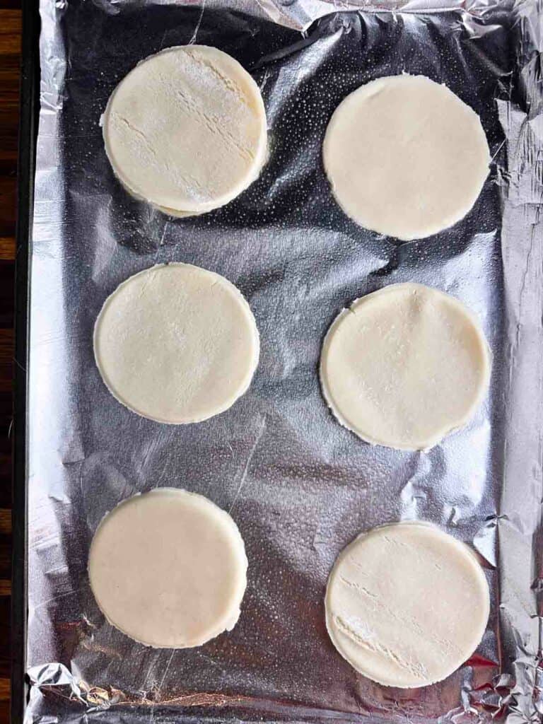Mini apple pie crusts on a baking sheet.