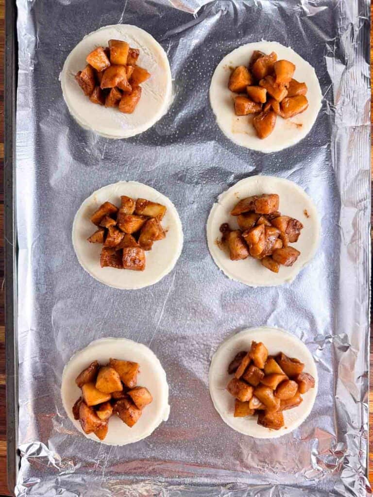 Mini pie crusts with apple pie filling on each.