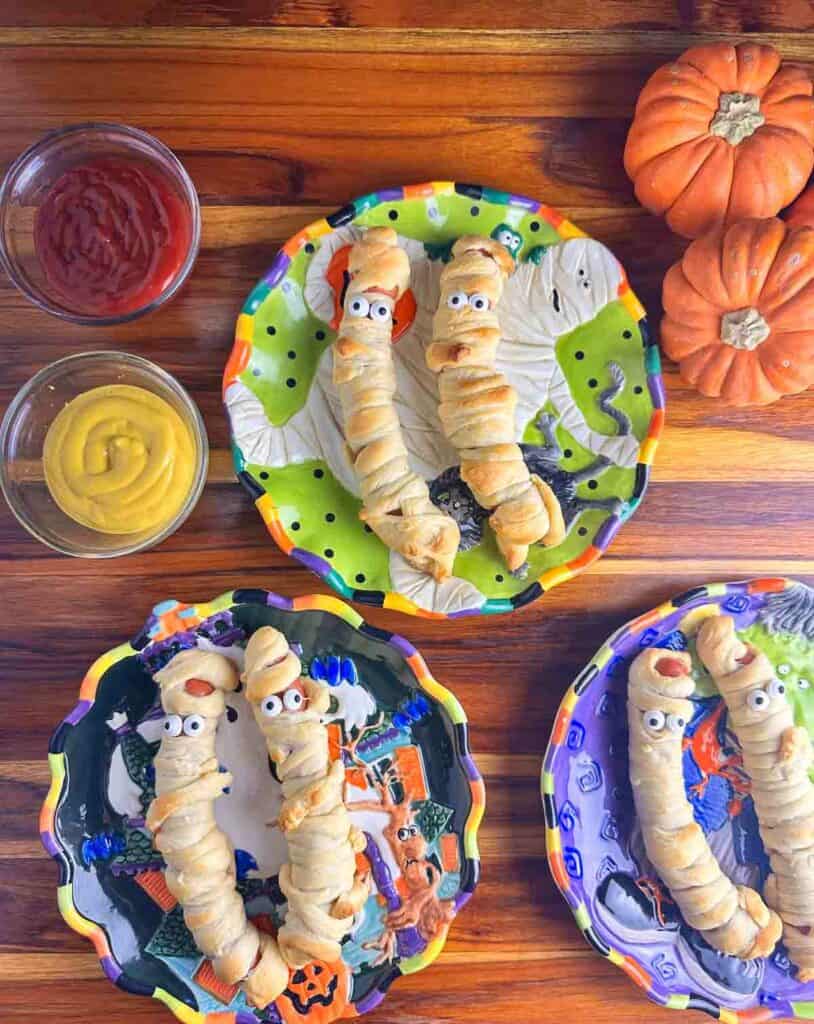 Several plates of mummy hot dogs ready to eat.