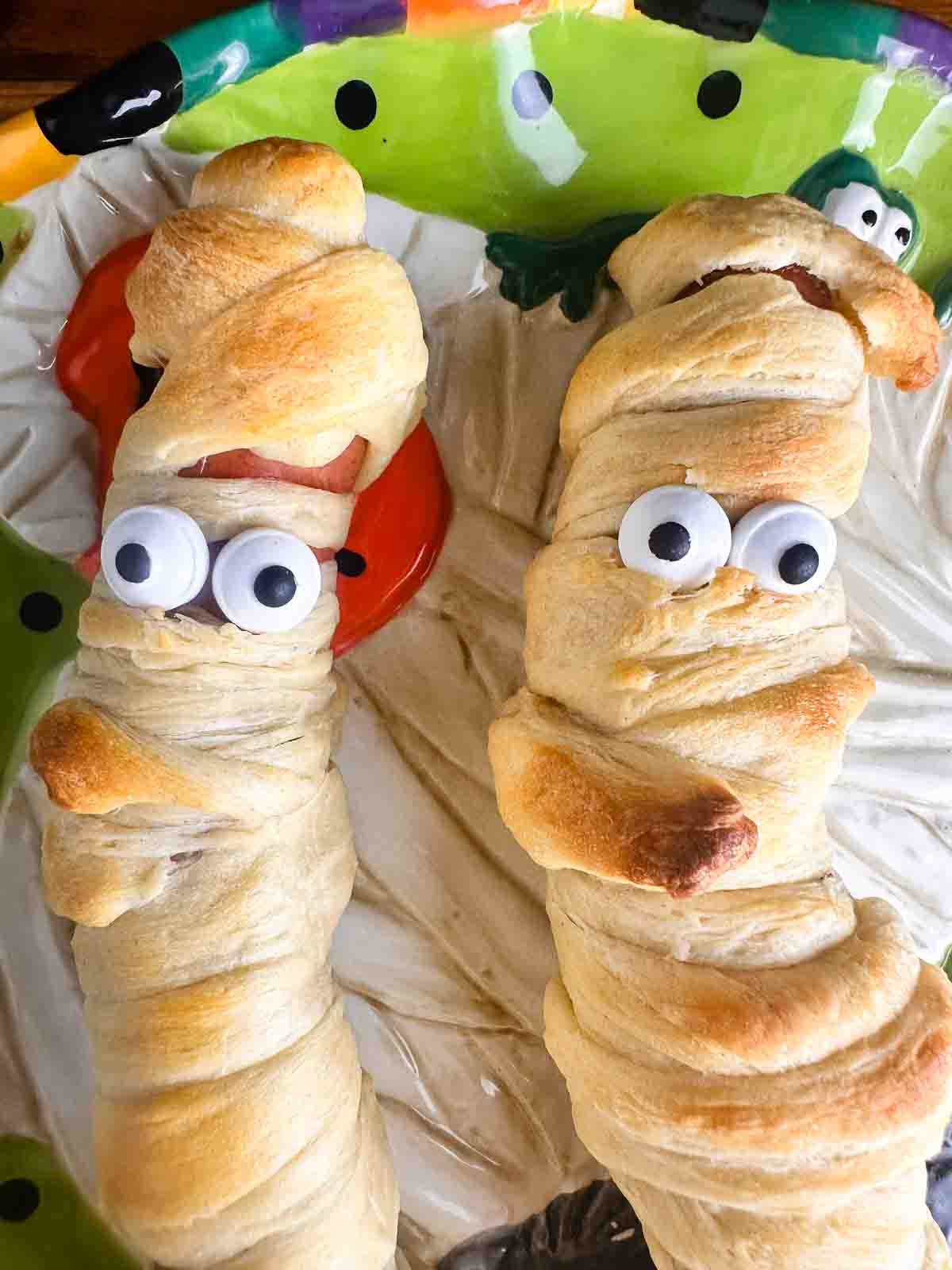 Plate of mummy hot dogs ready to eat.