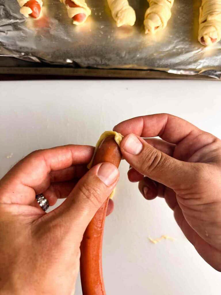 Wrapping a hot dog for mummy hot dogs, starting at the top.