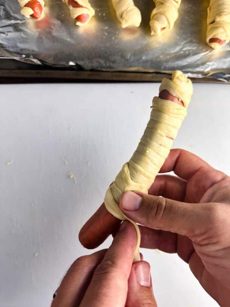 Hot dog getting wrapped up like a mummy for Halloween.