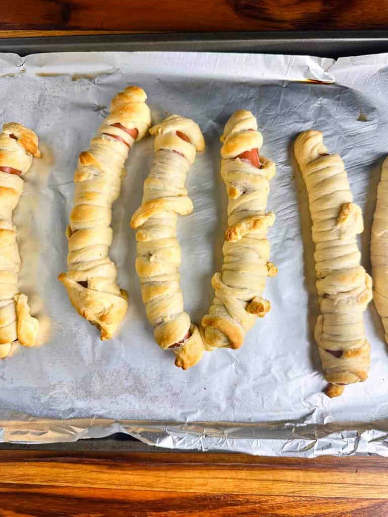 Baked hot dogs with crescent rolls wrapped around them to create mummies.