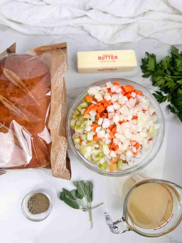 Ingredients for sourdough stuffing: butter, sourdough, miroux poix, parsley, seasonings, fresh sage, and chicken or turkey broth.